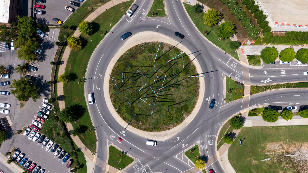 about-us-img Drone shot of a city roundabout with vehicles, showcasing traffic flow and urban design.