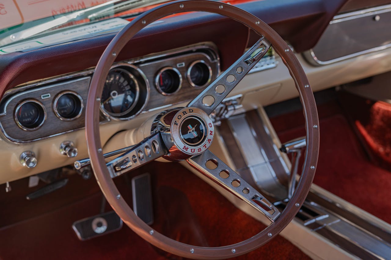 services-img-01 Close-up of a vintage Ford Mustang steering wheel showcasing the timeless design and iconic car dashboard.